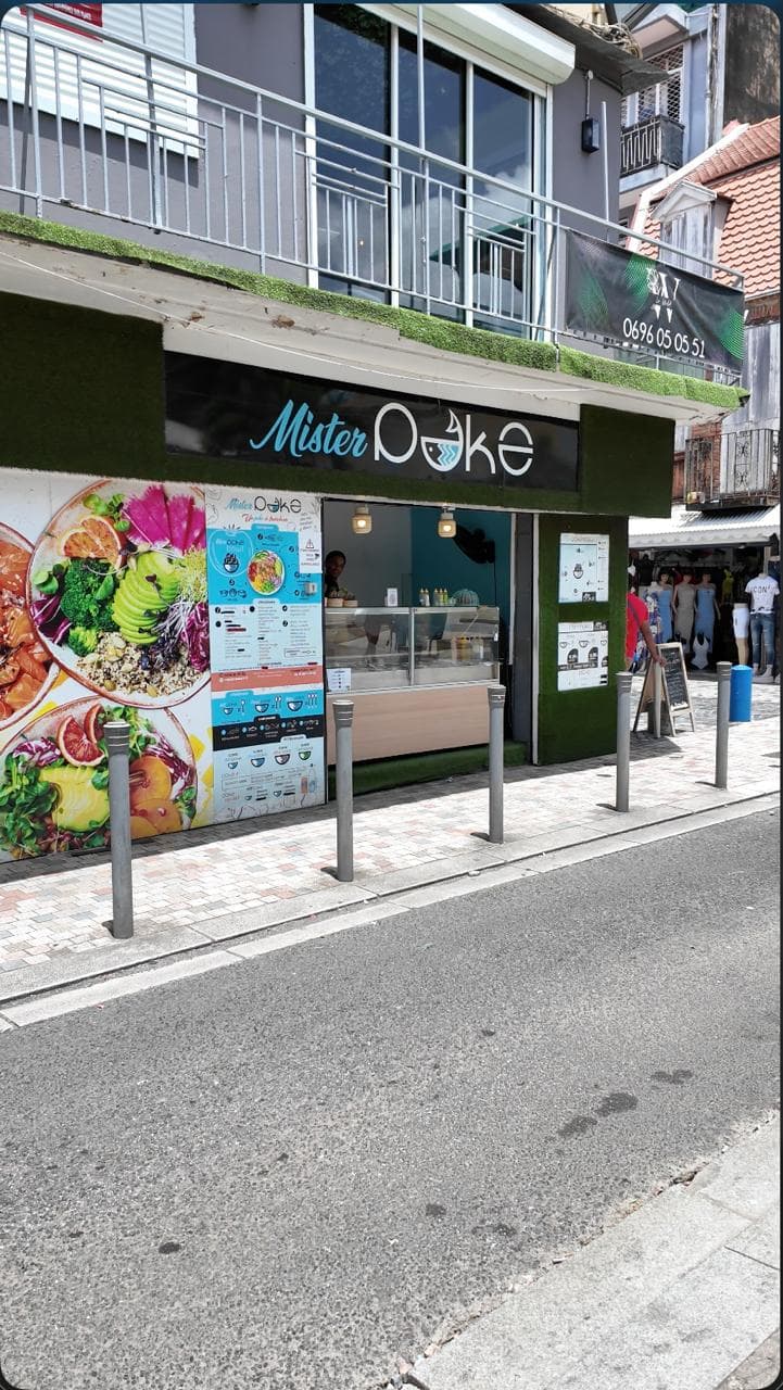 La devanture de Mister Poke, façade en gazon synthétique, grande photo de bols colorés et comptoir ouvert sur la rue.